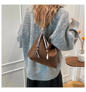Borsa tote in pelle marrone con foulard di seta indossata da una modella stile casual