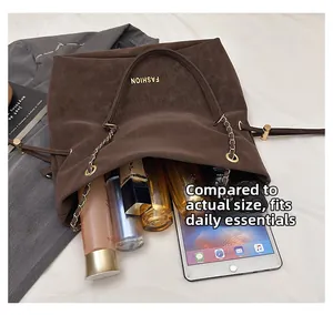 Detail view of large brown chain bag capacity with daily essentials and gold lettering