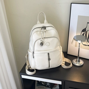 Detail eines cremeweißen Rucksacks aus Kunstleder mit Kieseltextur und Seitentaschen
