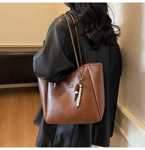 Détail du sac cabas marron en similicuir avec étiquette de mode et pendentif en perles