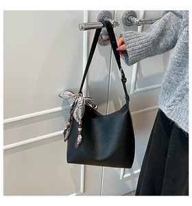Detail of black textured leather bag with paisley silk scarf and ethnic wooden beads