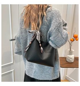 Dettaglio della borsa a secchiello nera in pelle con foulard paisley e perline etniche