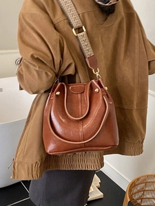 Vintage caramel brown bucket bag with an adjustable geometric woven shoulder strap