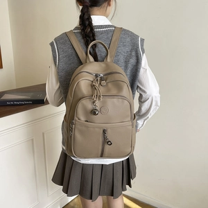 Detailansicht eines khakifarbenen Rucksacks aus Leder mit Narbenstruktur getragen vom Model