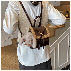 Detail of vintage brown leather mini backpack with plush trim and rabbit charm on model