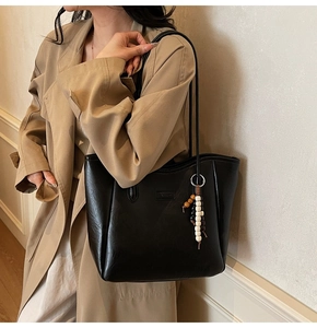 Détail du grand sac cabas noir avec texture en cuir mat et breloque en perles décorative