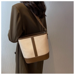 Detail der Canvas-Eimertasche mit braunem Lederbesatz, von Model in Straßenansicht getragen