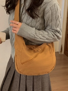 Grand sac bandoulière en toile jaune moutarde porté par un mannequin pour un look décontracté