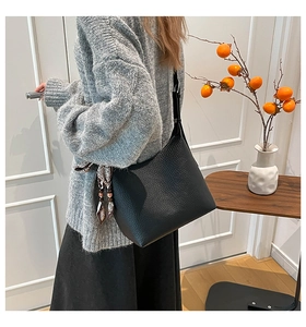 Dettaglio della borsa a secchiello in pelle martellata nera con foulard di seta marrone