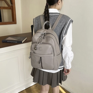 Detailansicht eines grauen Lederrucksacks mit Funktionsfächern und Metall-Reißverschlüssen