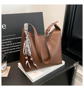 Close-up of brown litchi pattern leather tote bag with silk scarf and wooden bead detail