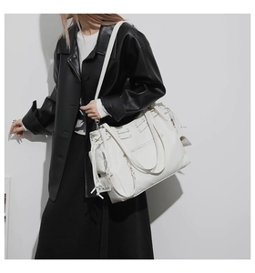 Close-up of white deconstructed tote bag featuring decorative cords and metal grommets