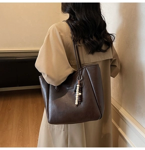 Détail du sac cabas marron café avec texture cuir et pendentif décoratif en perles