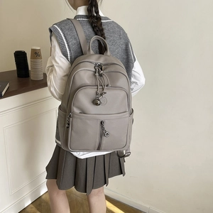 Detailansicht eines grauen Rucksacks aus strukturiertem Leder mit Metallring-Reißverschluss