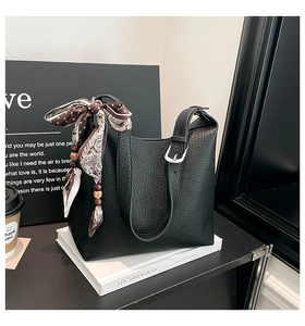 Detail of black lychee grain leather bucket bag with decorative paisley silk scarf