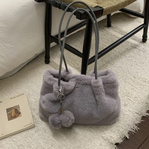 Dettaglio borsa a secchiello in ecopelliccia lavanda con pompon e tracolla grigia