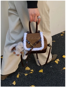 Detailed view of a dark brown leather bag with white plush trim and cute rabbit pendant