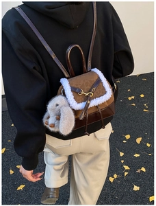 Detail of a brown leather backpack with white faux fur trim and a cute rabbit charm