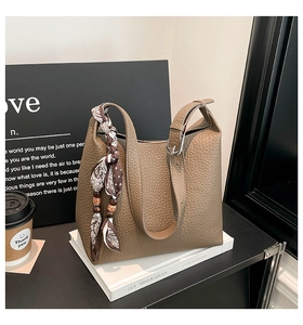 Close-up of deep brown lychee grain leather bucket bag with decorative silk scarf and wood beads