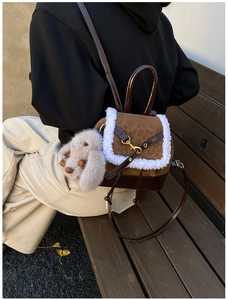 Detail of a brown suede bucket bag featuring leopard trim and a grey bunny plush charm