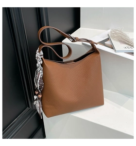 Dettaglio macro della borsa hobo in pelle marrone con ciondolo a foulard e tracolla regolabile