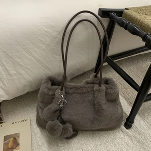 Détail du sac seau gris en fausse fourrure avec breloques pompon et cœur décoratif