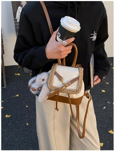 Detail of retro white and brown backpack with faux shearling trim and plush rabbit charm