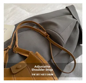 Detailaufnahme des verstellbaren Riemens und der weißen Naht auf brauner Velourtasche