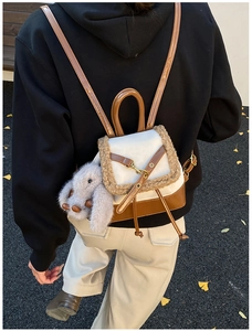 Detail of a mini leather and fleece backpack with a cute rabbit plush charm