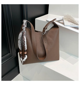 Dettaglio borsa a secchiello in pelle marrone scuro con foulard etnico decorativo