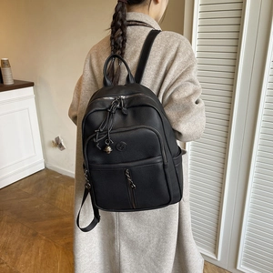 Detailansicht des schwarzen Rucksacks mit Lychee-Textur, Reißverschlüssen und Glockenanhänger