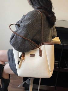 Grand sac cabas rétro crème et marron avec pompon perlé porté par un mannequin femme