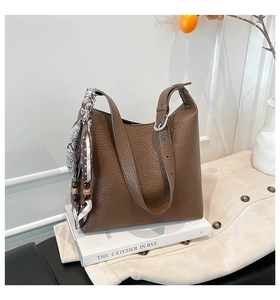 Dettaglio borsa a secchiello in pelle marrone con foulard stampato e perle in legno