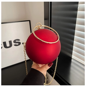 Detail of red spherical acrylic clutch bag with gold ring handle and metal chain strap