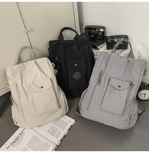 Detailed display of casual nylon backpacks in beige, black, and grey with front pockets