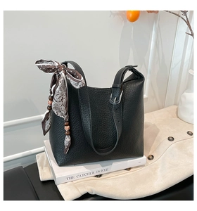 Dettaglio della borsa a secchiello in pelle martellata nera con foulard di seta