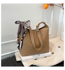 Dettaglio della borsa a secchiello in pelle marrone con foulard decorativo in seta stampata