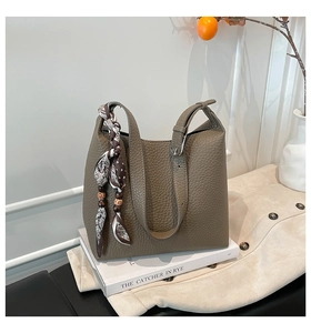 Dettaglio della borsa a secchiello in pelle martellata kaki con foulard di seta e perline di legno