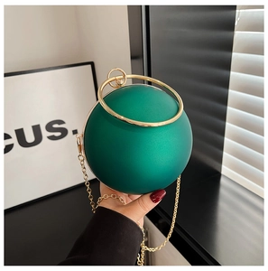 Detail of spherical dark green acrylic evening bag with gold ring handle and chain