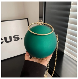 Close-up of matte dark green spherical evening bag with gold circular handle and chain