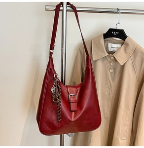 Detail of dark red vintage hobo bag with silver buckle hanging on a coat rack