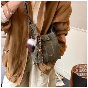 Detail einer grünen Wildleder-Eimertasche mit Kontrastnähten und Plüschhandschuh
