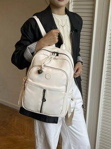 Schicker beiger Kunstleder-Rucksack mit Fächern und Glockenanhänger am Modell