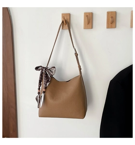 Close-up of brown litchi grain leather shoulder bag with polka dot silk scarf detail