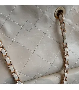 Detail of cream quilted PU leather bag with pale gold chain strap and stitching