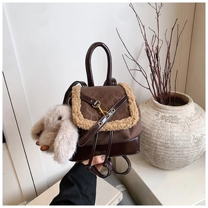 Detail of a brown monogram backpack with beige faux fur trim and a plush rabbit charm