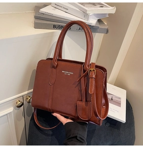 Macro view of textured dark brown matte leather tote bag with elegant golden logo detail