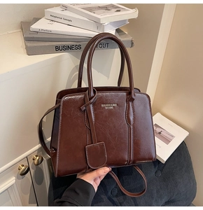 Close-up of vintage dark brown glossy leather handbag with metallic logo and strap