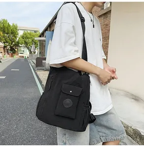 Outdoor street style shot of a large black waterproof crossbody bag with wide strap