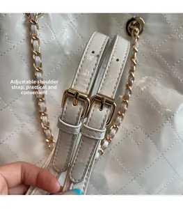 Close-up of adjustable leather shoulder strap with gold pin buckle on white chain bag